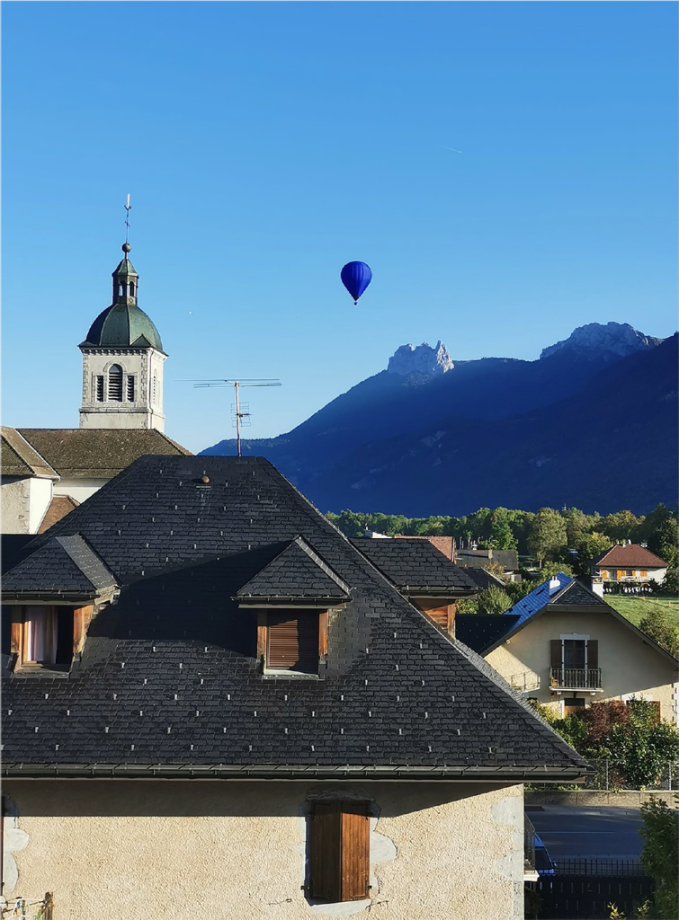 Photo d'un village avec une montage et une mongolfière dans le fond