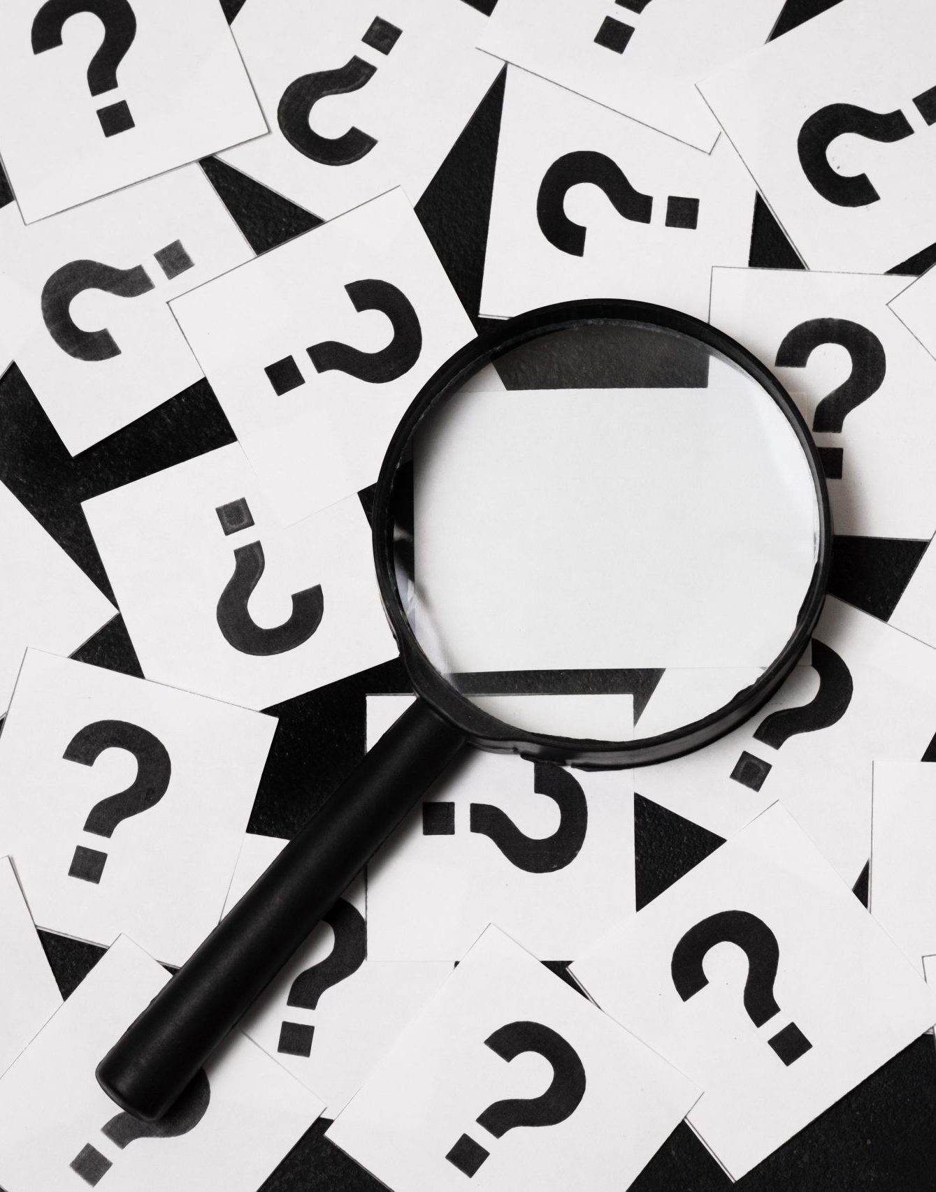 Photo d'un loupe sur une pile de "cartes postales" avec un point d'intérogation dessus